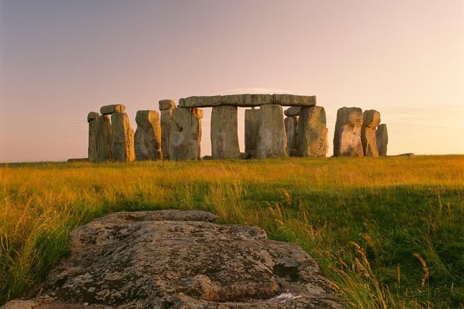 Stonehenge across the grass of Salisbury Plain with a fallen stone in the foreground