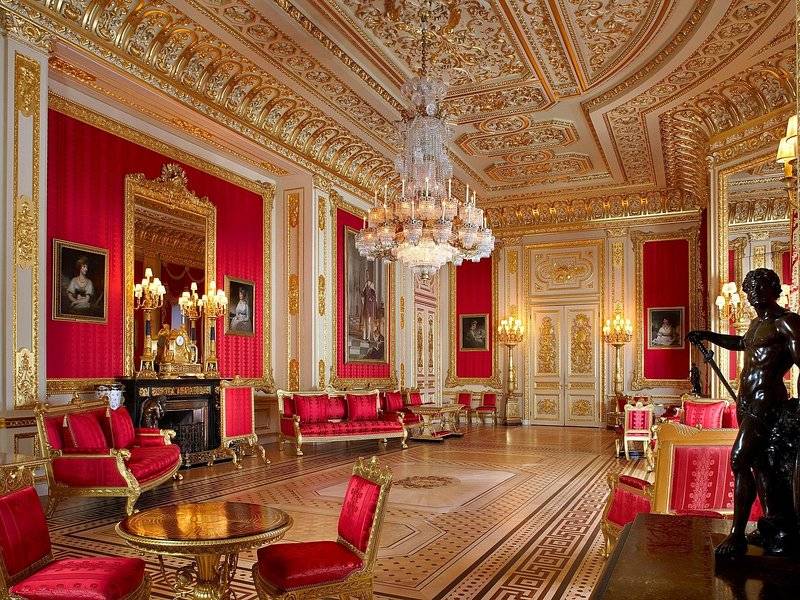 A red-walled state apartment at Windsor Castle under a chandelier